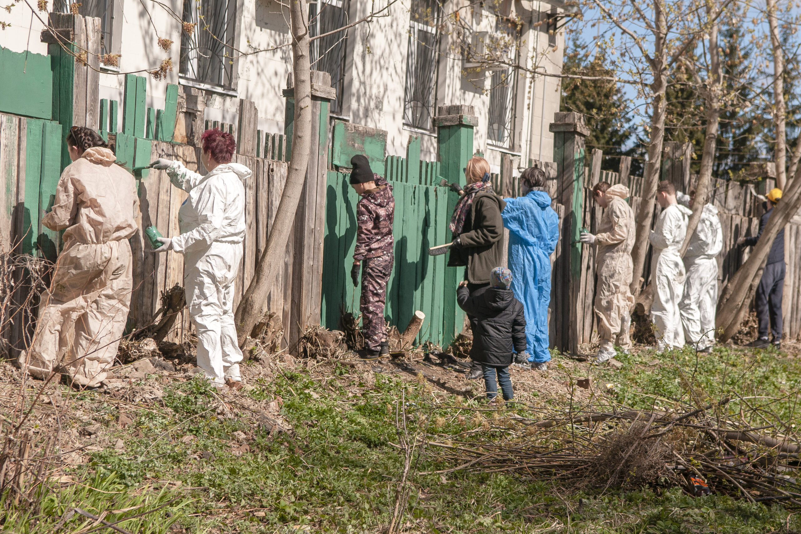 Волонтёры красят забор на субботнике в Доме Корзинкина в Костроме 2023